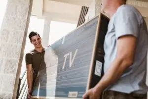 Two men carrying a TV up a staircase.