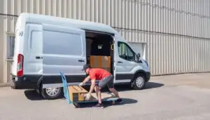 Delivery professional loading a cargo van with heavy boxes.