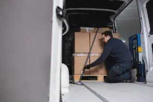 Worker securing pallet of large boxes inside delivery van | big and bulky last-mile delivery